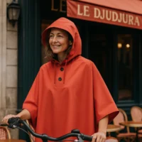 Femme élégante portant une cape de pluie vélo Badawin rouge devant un café