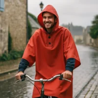 Homme à vélo sous la pluie portant une cape de pluie vélo Badawin rouge