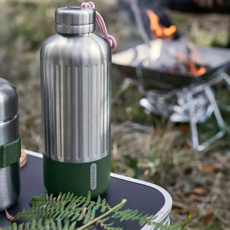 Gourde inox 850 ml olive Black+Blum utilisée en camping près d’un feu