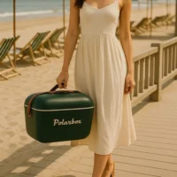 Jeune femme en robe d'été portant la glacière Polarbox Green Forest sur la plage.