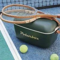 Glacière Polarbox Green Forest posée sur un court de tennis avec raquettes vintage.