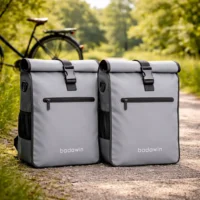 Lot de 2 sacoche vélo Aaron grises Badawin posées sur chemin de campagne.