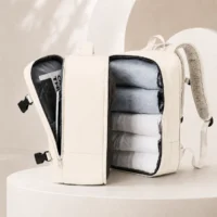 Sac à dos de voyage blanc cassé ouvert comme une valise avec vêtements rangés