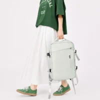 Sac à dos de voyage extensible vert clair porté à la main avec tenue décontractée