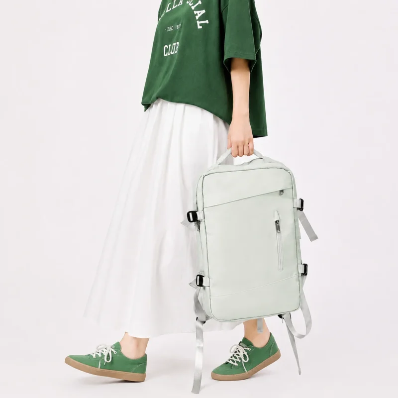 Sac à dos de voyage extensible vert clair porté à la main avec tenue décontractée